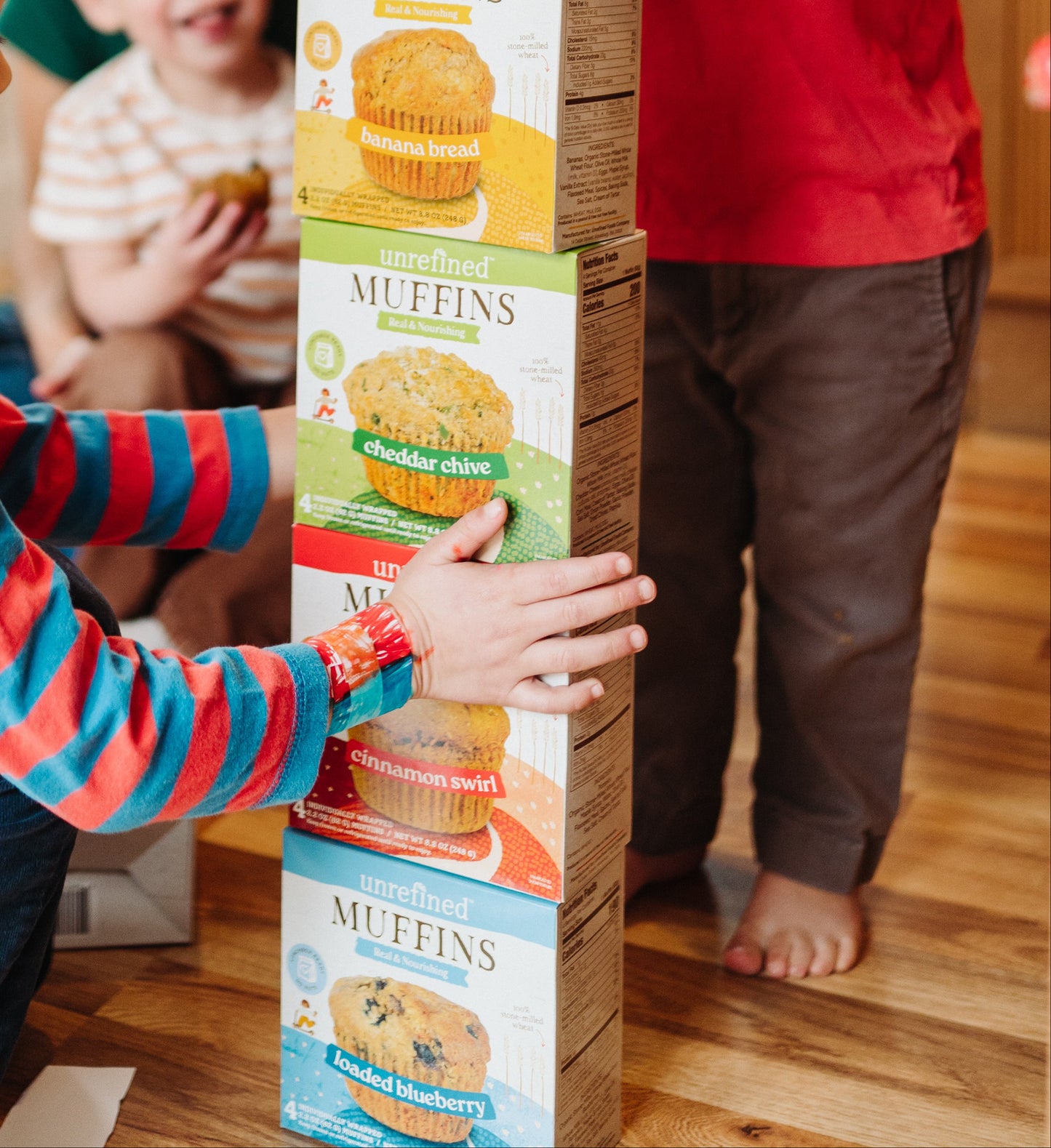 Children playing with a stack of muffin boxes indoors