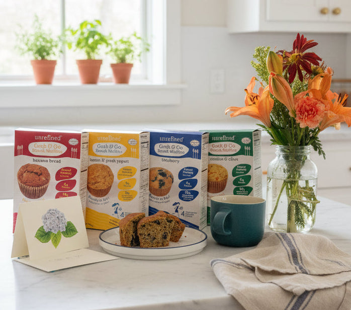 Kitchen counter with muffin tins, a mug, and a vase of flowers on a white countertop.