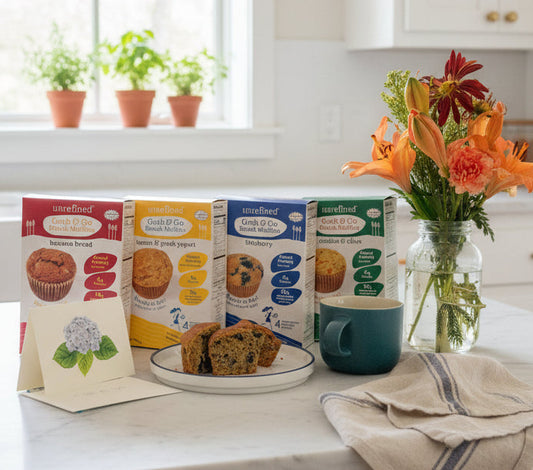 Kitchen counter with muffin tins, a mug, and a vase of flowers on a white countertop.