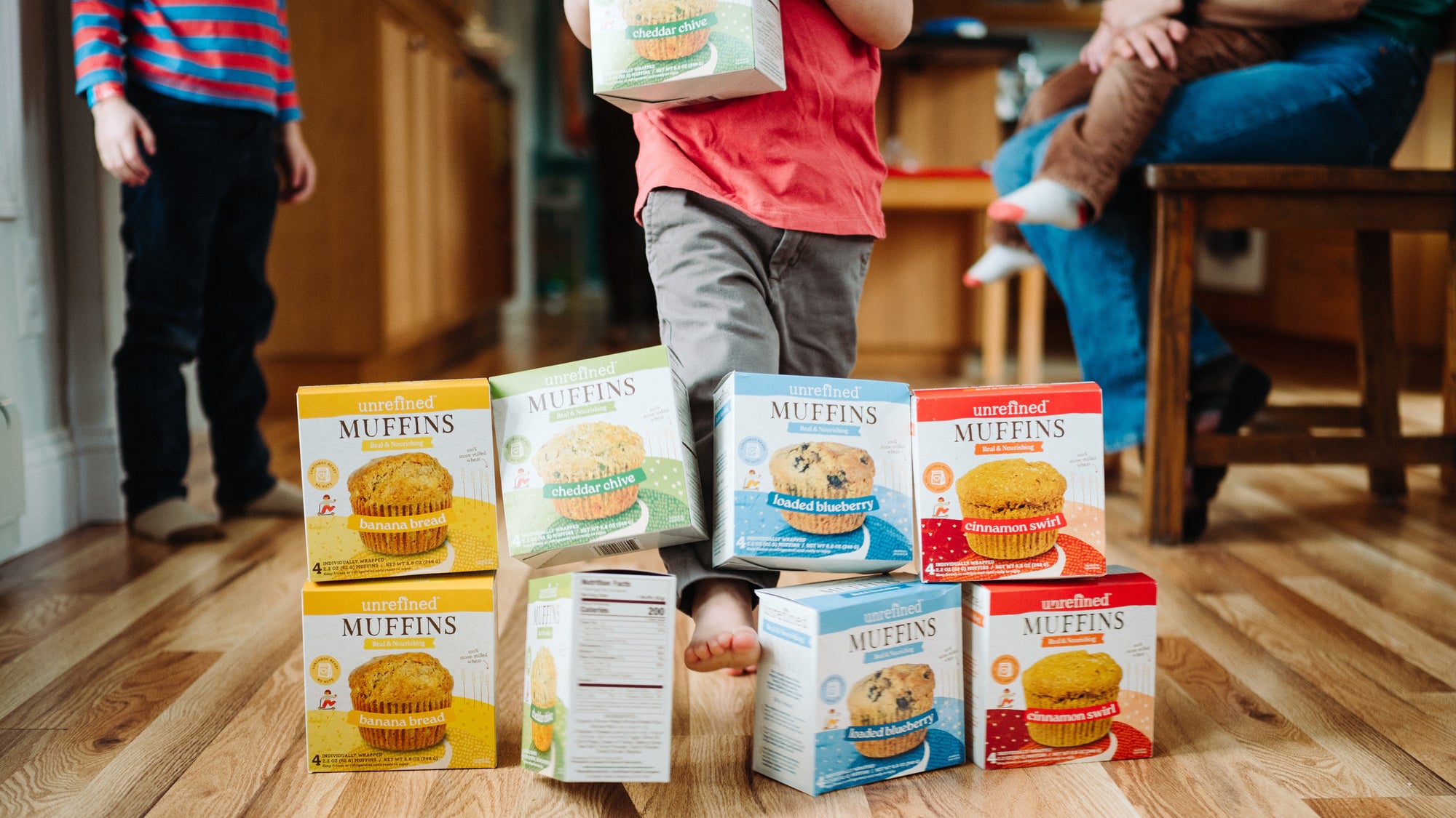young child kicking boxes of blueberry muffins